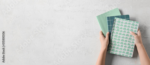 Child's hands with different notebooks on light background with space for text © Pixel-Shot