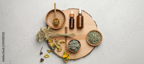 Canvas Print Different dried herbs and bottles of essential oil on light background