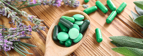 Billede på lærred Spoon with plant based pills on wooden background