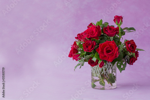 Red rose flowers in vase, green leaves, close up,