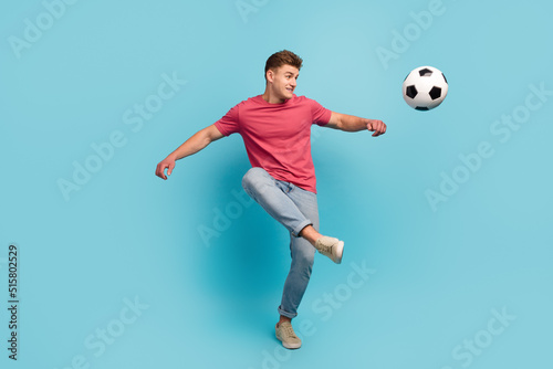 Full length photo of young man play soccer kick ball hobby sportive isolated over blue color background