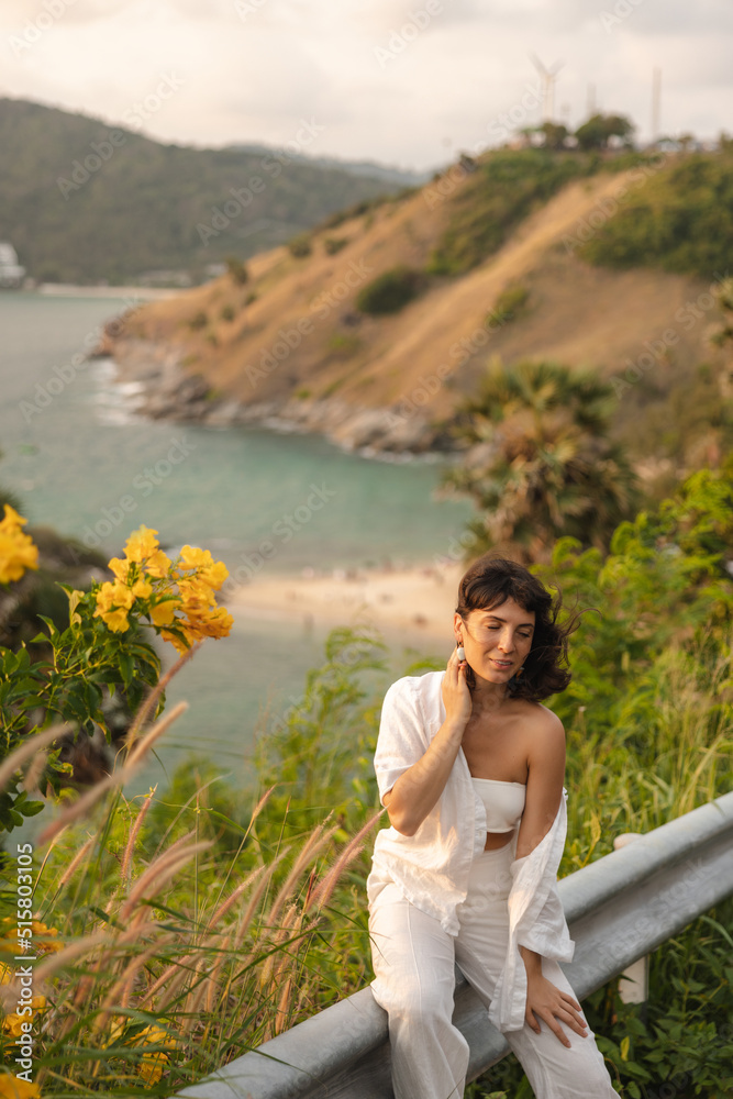 Beauty caucasian young girl outdoors enjoying nature on background of sea. Brunette wear white top, shirt and pants. Relaxed lifestyle, concept