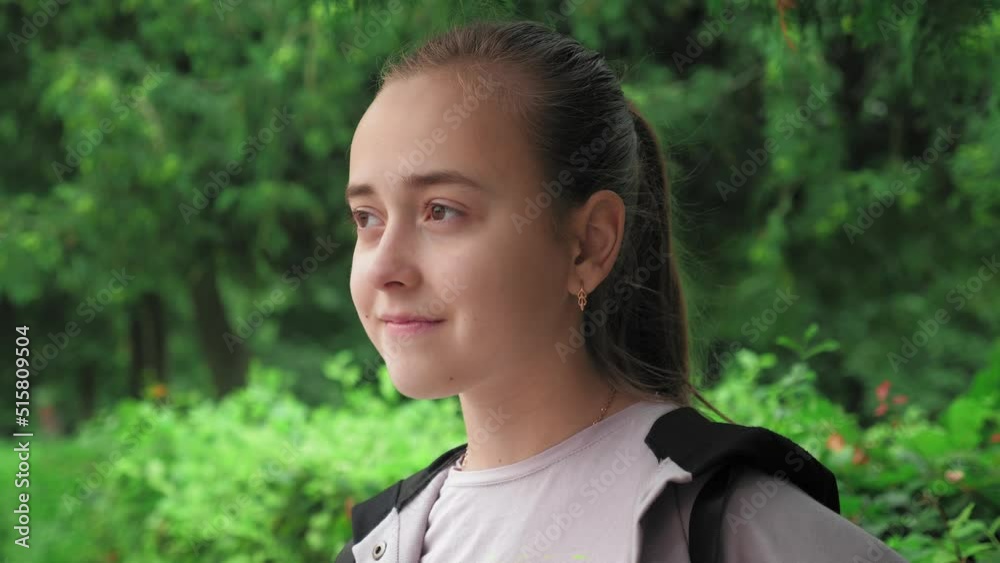 Portrait of a young beautiful girl standing in the park. A girl with her hair gathered in a ponytail enjoys the beauty of nature. Portrait of a young beautiful girl standing in the park. A girl with her hair gathered in a ponytail enjoys the beauty of nature.