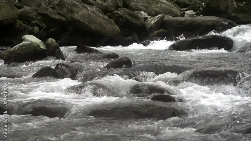 River with white water rapids breaking apart over large stones in river, filmed in slow motion on cloudy day River with white water rapids breaking apart over large stones in river, filmed in slow motion on cloudy day
