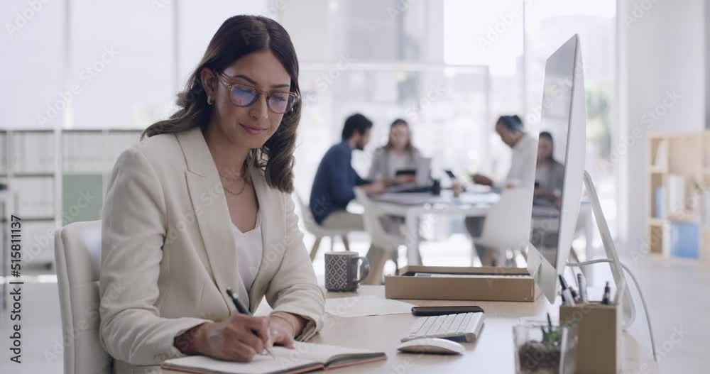 Happy young business woman using a computer and writing notes in her diary at the office. A female entrepreneur thinking, planning and drawing up a strategy to grow and develop a new startup company