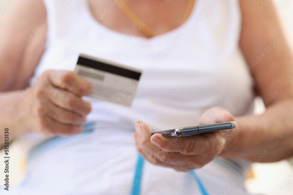 Elderly female making e-payments using smartphone and credit card Elderly female making e-payments using smartphone and credit card