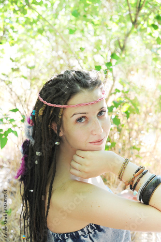 Beautiful young woman portrait with dreadlocks hairstyle decorated assorted beads and colored feathers
