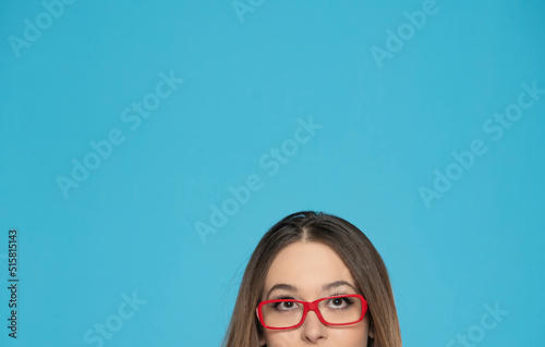 half portrait of a young woman with glasses looking up on a blue background