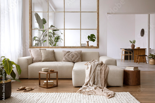 Modern open space interior with design modular sofa, furniture, wooden coffee tables, tropical plants and elegant personal accessories in stylish home decor. Template.