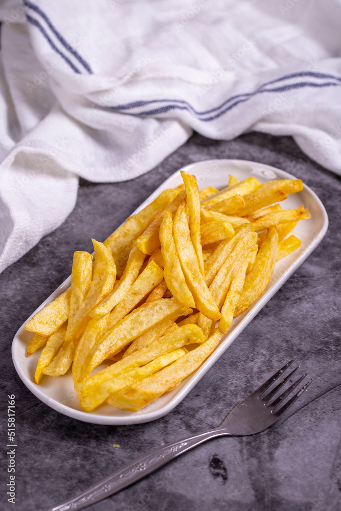 Fried potatoes. French fries on dark background. French fries served on a plate. close up Fried potatoes. French fries on dark background. French fries served on a plate. close up