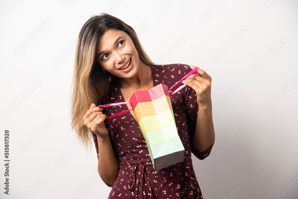 Young woman opening a small shop bag on white background Young woman opening a small shop bag on white background