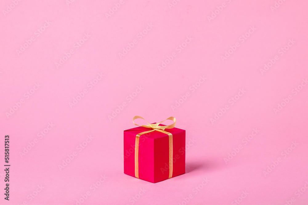 Small red gift box on pink background, minimal composition.