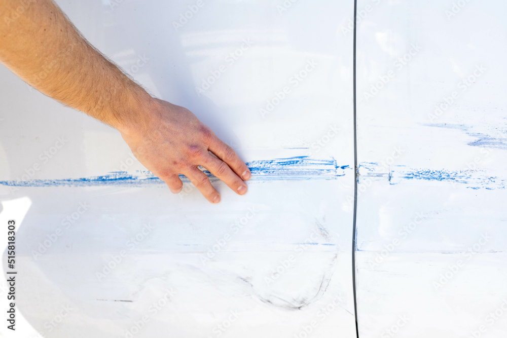 Man evaluating the damage in his car, done while it was parked in the street. Man evaluating the damage in his car, done while it was parked in the street.