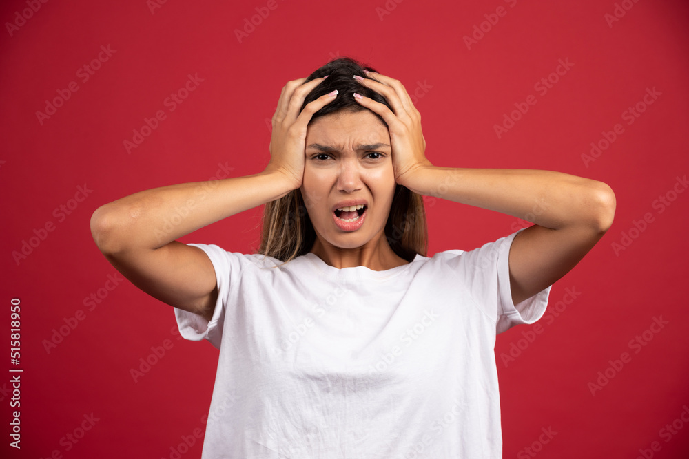 Young woman touching her head on red background