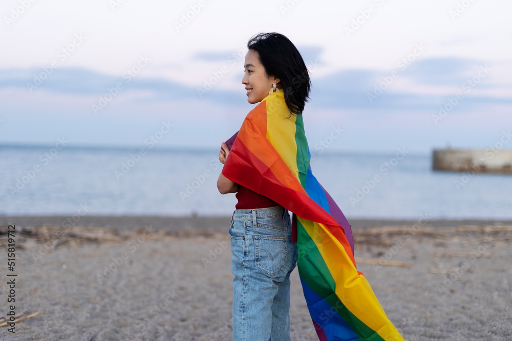 Happy girl with a pride flag at the beach. LGBT community