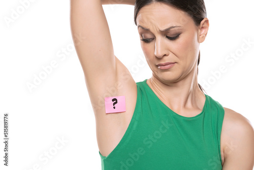 Woman shows her underarm with the question mark on her on white background