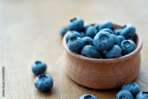 Fresh blueberries in a wooden bowl on wooden surface background. Concept for healthy nutrition.
