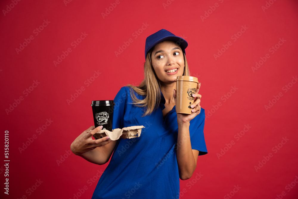 Young woman in blue uniform holding a carton of two cups Young woman in blue uniform holding a carton of two cups