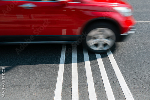 Vászonkép Rumble strips or speed breakers  on asphalt road surface and red car crossing them in motion blur