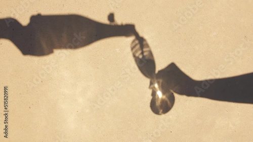 shades and silhouette concept - shadows of hands pouring wine from bottle to champagne glass