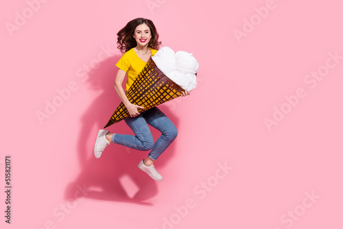 Full length photo of funky young brunette lady jump with pinata wear t-shirt jeans footwear isolated on pink background