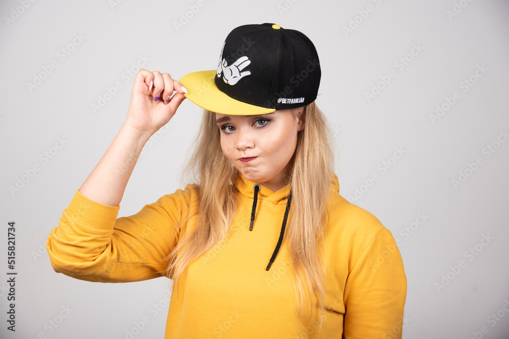 Portrait of young woman in hoodie posing with a stylish cap Portrait of young woman in hoodie posing with a stylish cap