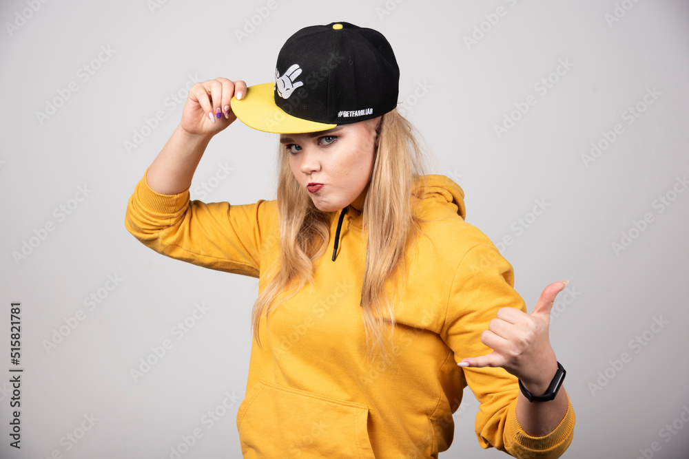 Portrait of young woman in hoodie posing with a stylish cap Portrait of young woman in hoodie posing with a stylish cap