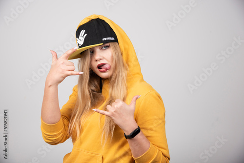 Portrait of woman in hoodie showing telephone sign