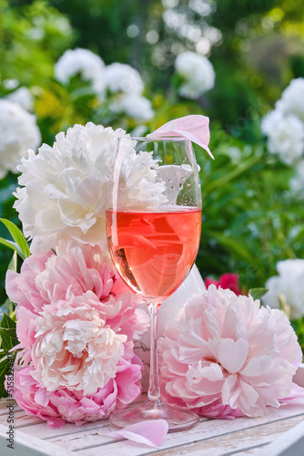 Fototapeta Naklejka Na Ścianę i Meble -  Still Life with white and pink peonies, rose wine against a blurred background in the garden. Concept of celebration party outdoors in a summer day.
