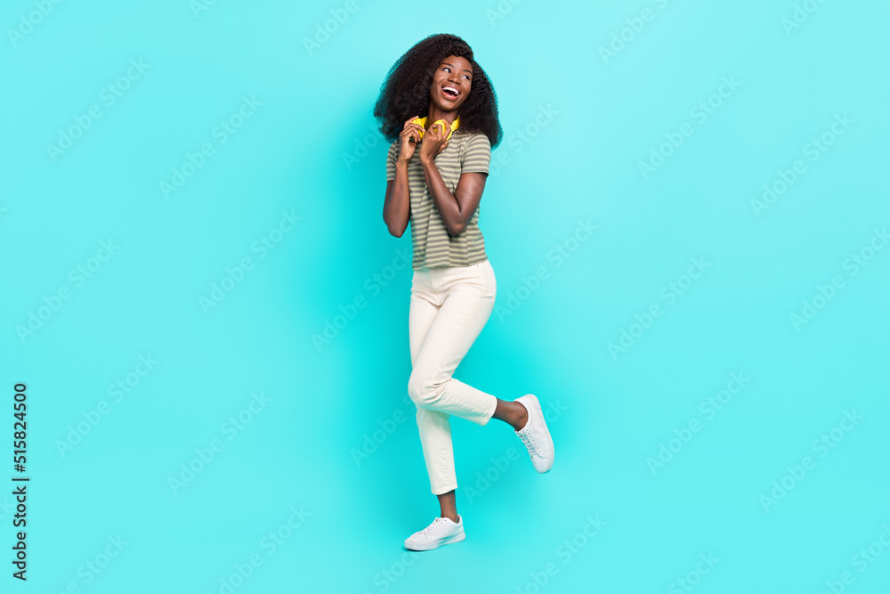 Full size portrait of lovely cute girl hands touch headphones look empty space isolated on bright aquamarine color background Full size portrait of lovely cute girl hands touch headphones look empty space isolated on bright aquamarine color background