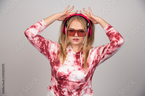 Blonde young woman in pink headphones holding her head