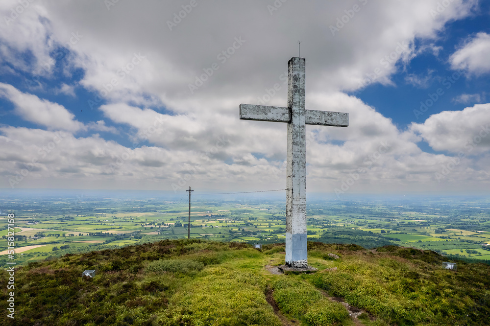 Tall white Catholic cross on top of Devils bit mountain in county Tipperary, Ireland. Aerial view. Beautiful landscape with green fields and forests in the background. Irish landscape.