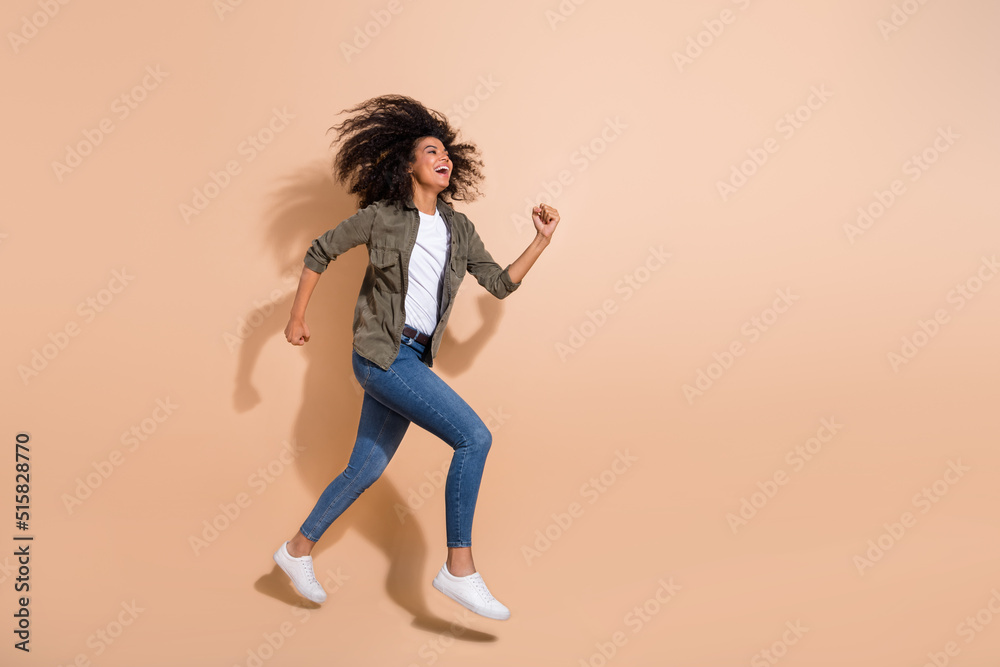Full length body size view of pretty cheerful girl jumping running enjoying isolated over beige pastel color background