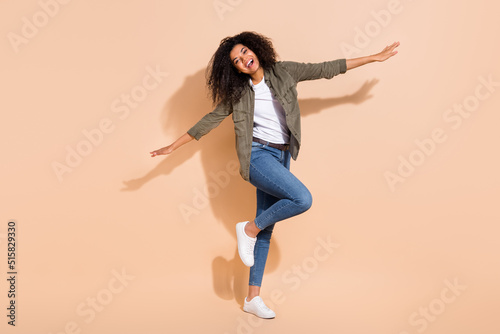 Full length body size view of attractive cheerful girl flying having fun isolated over beige pastel color background © deagreez