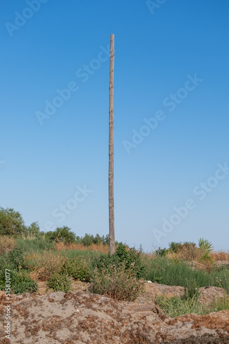 Old power pillar on a summer day. Power line post with electricity cables against a clear blue sky