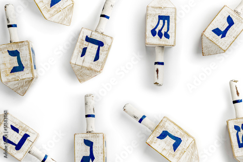 Dreidel also dreidle or dreidl with blue lettering on white background. Four-sided spinning top, played during the Jewish holiday of Hanukkah Jewish variant on the teetotum. Wooden gambling toy photo