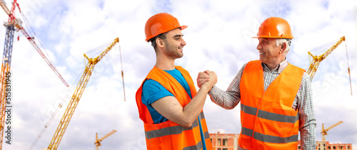 Φωτογραφία Older construction supervisor with younger worker helper at construction site