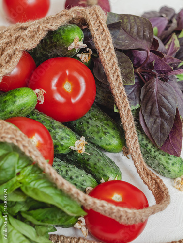 Fresh organic tomato, cucumber, basil in crochet jute bag. Zero waste. Eco friendly shopping. Healthy eating concept.