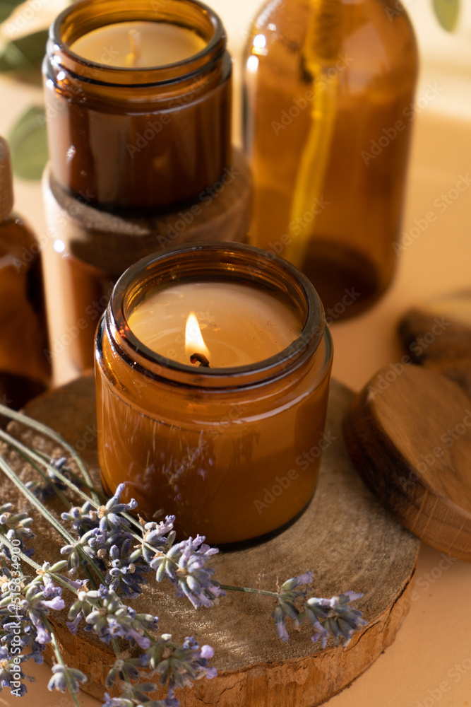 Soy candles in a glass jar. Aromatherapy. Burning candle and lavender. Wooden lid for jars. Beige background. Comfort and relaxation. Handmade. Home decor. Soy candles in a glass jar. Aromatherapy. Burning candle and lavender. Wooden lid for jars. Beige background. Comfort and relaxation. Handmade. Home decor.