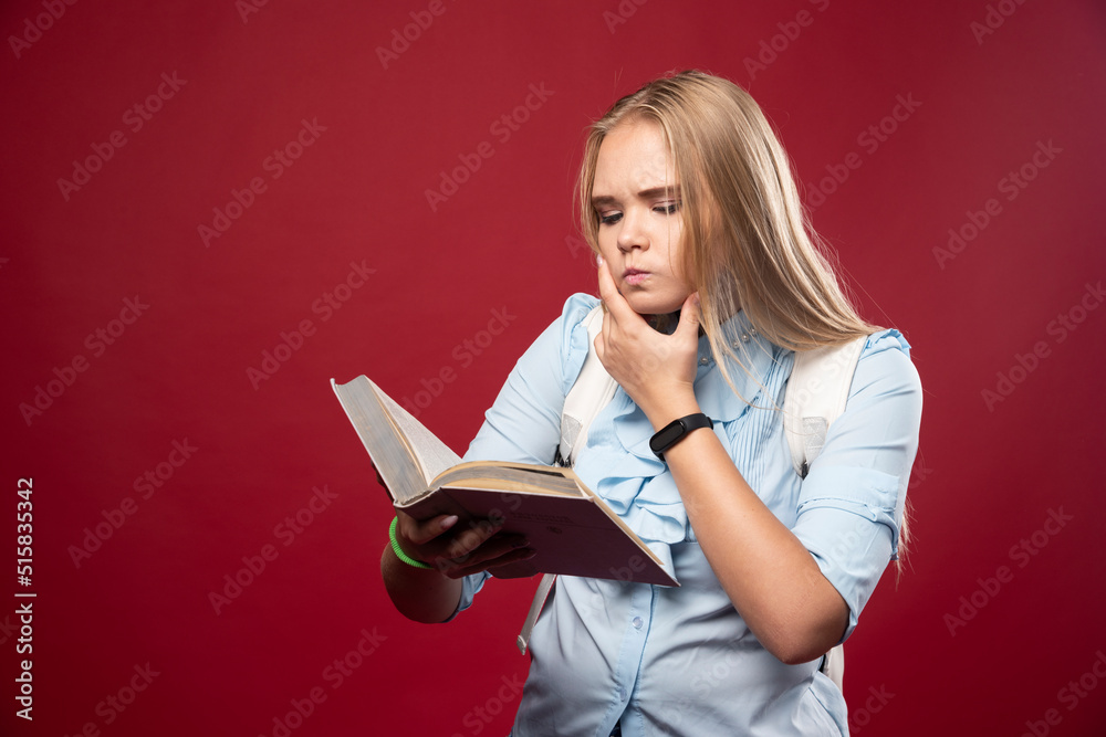 Blonde studentgirl reads a book and thinking carefully Blonde studentgirl reads a book and thinking carefully