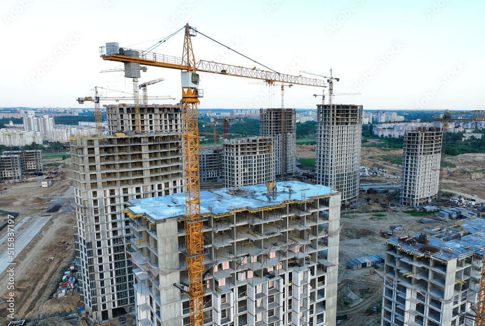 Сonstruction site with tower cranes on building construction. Builder on formworks. Cranes on pouring concrete in formwork. Tower cranes on construction in built environment. Buildings renovation..