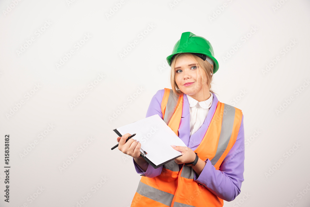 Young female contractor with green helmet opened clipboard on white background Young female contractor with green helmet opened clipboard on white background