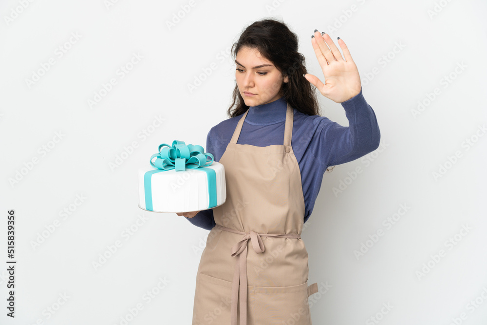 Pastry Russian chef holding a big cake isolated on white background making stop gesture and disappointed Pastry Russian chef holding a big cake isolated on white background making stop gesture and disappointed