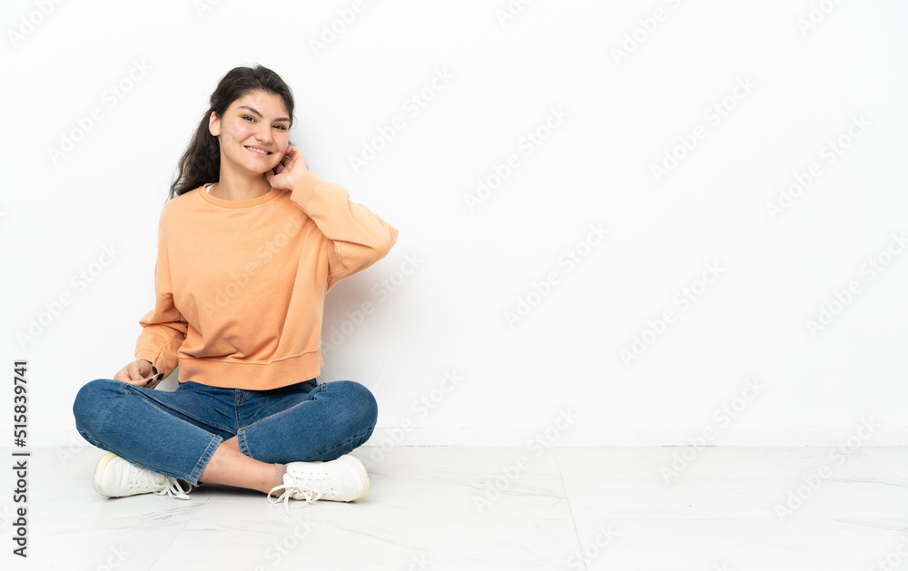 Teenager Russian girl sitting on the floor laughing Teenager Russian girl sitting on the floor laughing