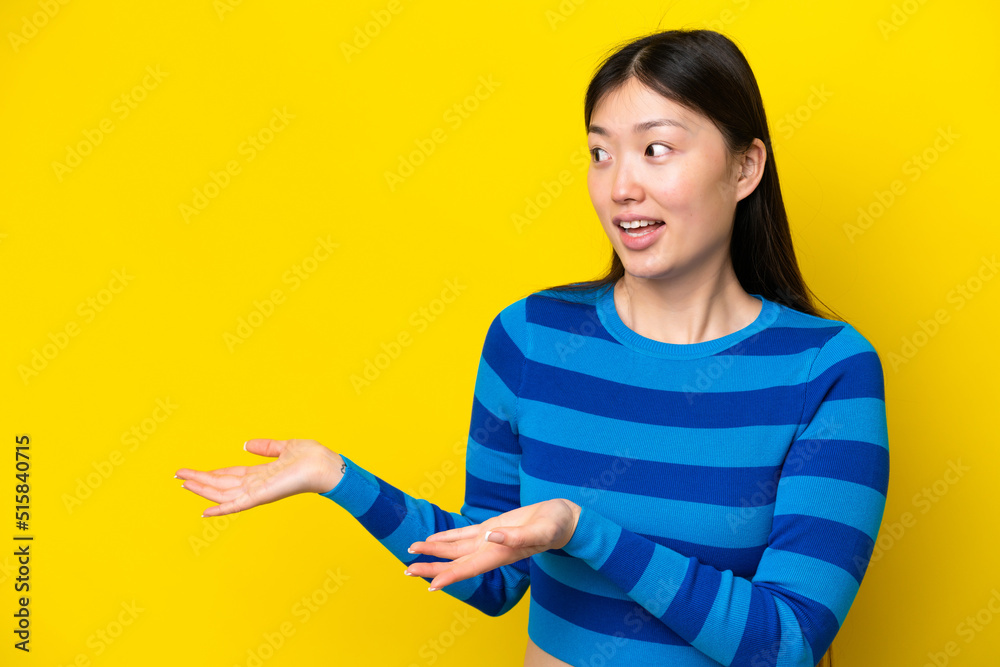 Young Chinese woman isolated on yellow background with surprise expression while looking side Young Chinese woman isolated on yellow background with surprise expression while looking side