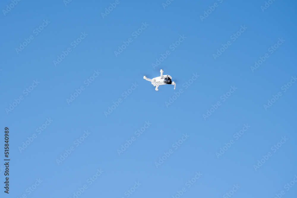 Quadcopter drone flies against the backdrop of snow-capped mountains and blue sky Quadcopter drone flies against the backdrop of snow-capped mountains and blue sky
