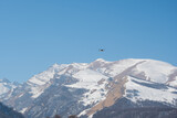 Quadcopter drone flies against the backdrop of snow-capped mountains and blue sky