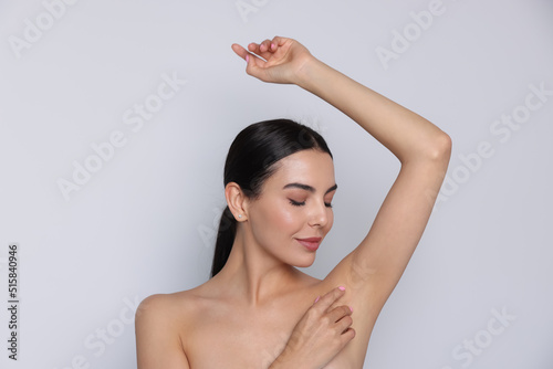 Young woman showing smooth skin after epilation on white background