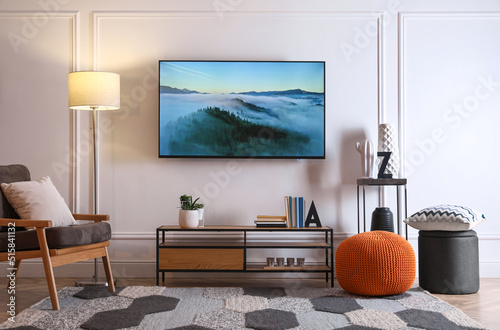 Stylish room interior with modern TV, armchair and decor photo