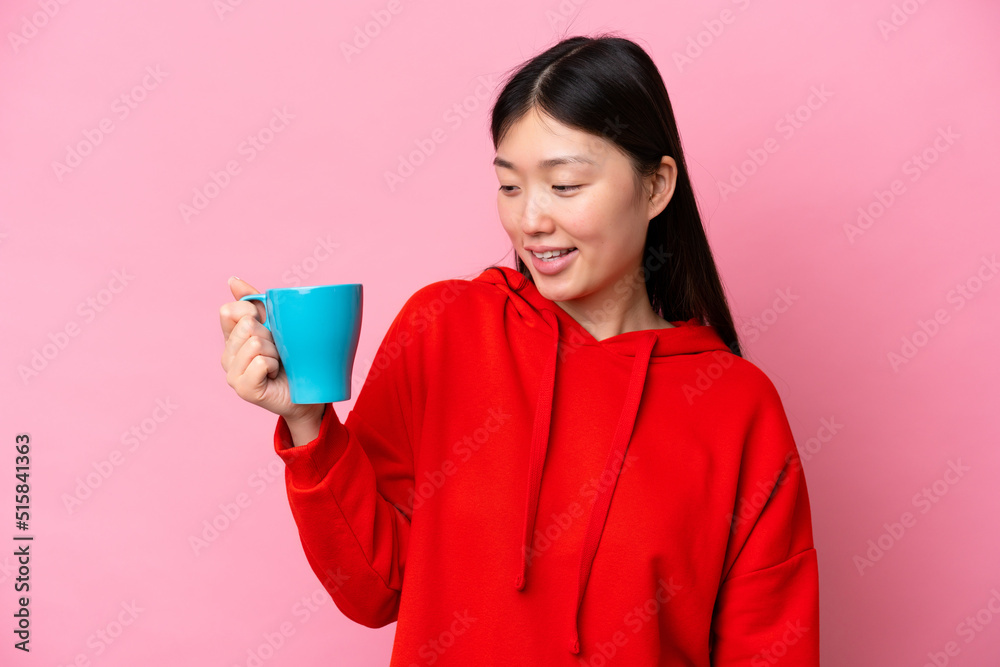 Young Chinese woman holding cup of coffee isolated on pink background with happy expression Young Chinese woman holding cup of coffee isolated on pink background with happy expression